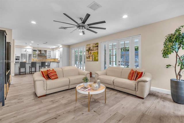 living room featuring light hardwood / wood-style floors, french doors, and a healthy amount of sunlight