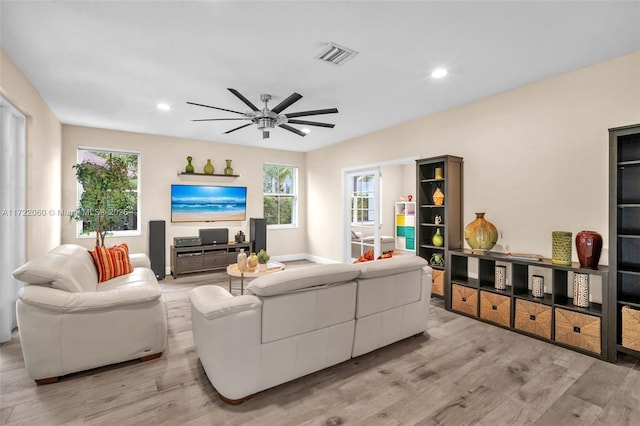 living room with ceiling fan, a wealth of natural light, and light wood-type flooring