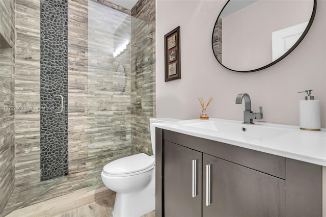 bathroom featuring toilet, vanity, and a tile shower