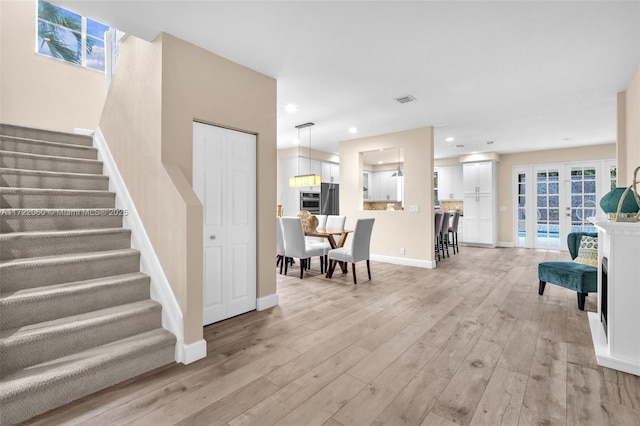 living room featuring french doors and light wood-type flooring