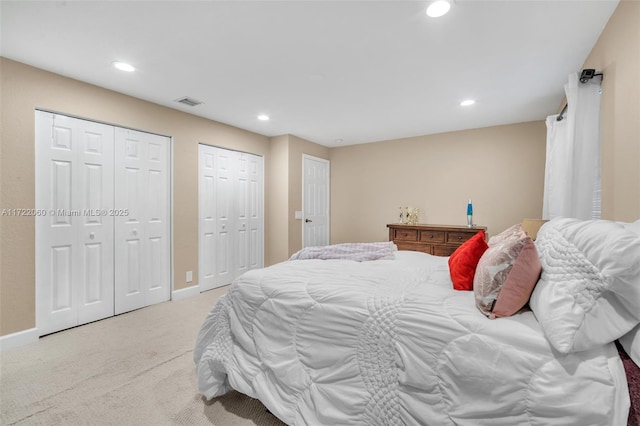 bedroom with light carpet and multiple closets