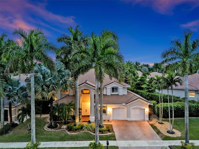 mediterranean / spanish-style home featuring a garage and a yard