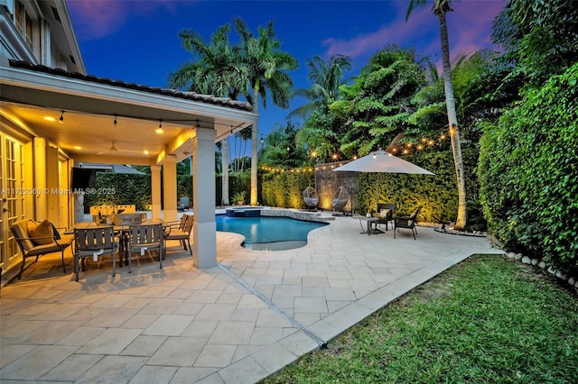 pool at dusk featuring a patio