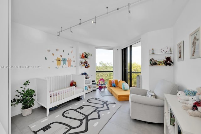 bedroom featuring a crib, expansive windows, and track lighting