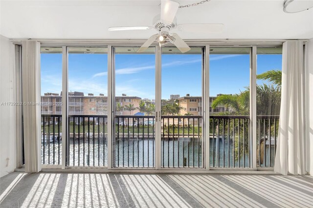 unfurnished sunroom featuring ceiling fan and a water view