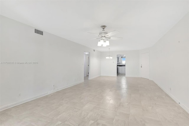 spare room featuring ceiling fan with notable chandelier