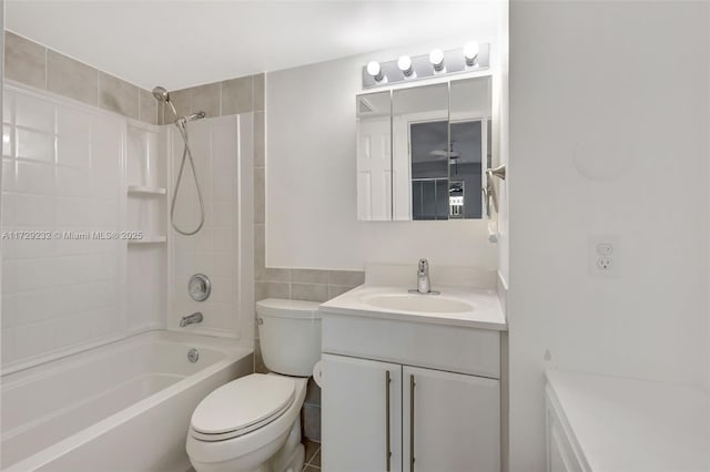 full bathroom featuring shower / bath combination, toilet, vanity, and tile walls