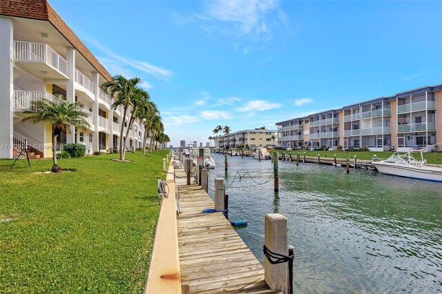 view of dock with a lawn and a water view