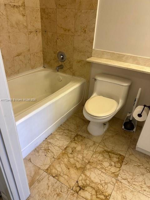 bathroom with toilet and tiled shower / bath combo