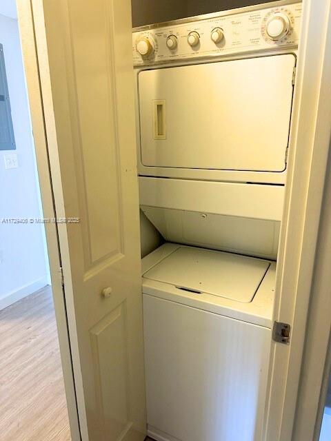 clothes washing area featuring stacked washer / drying machine and light hardwood / wood-style flooring