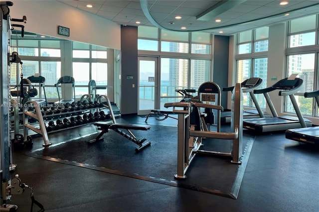 gym featuring a paneled ceiling, floor to ceiling windows, and a wealth of natural light