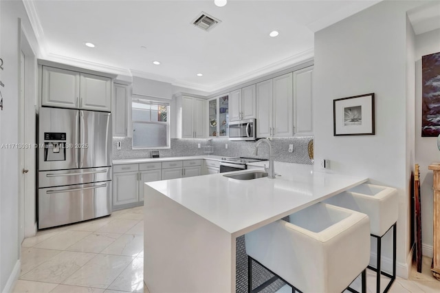 kitchen featuring kitchen peninsula, a kitchen bar, sink, stainless steel appliances, and ornamental molding