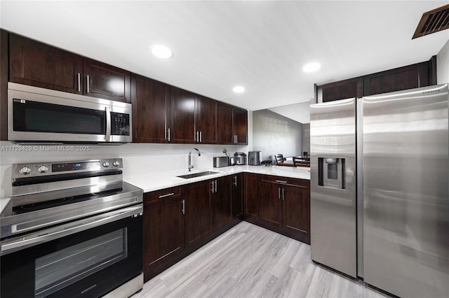 kitchen with dark brown cabinetry, sink, stainless steel appliances, and light hardwood / wood-style floors