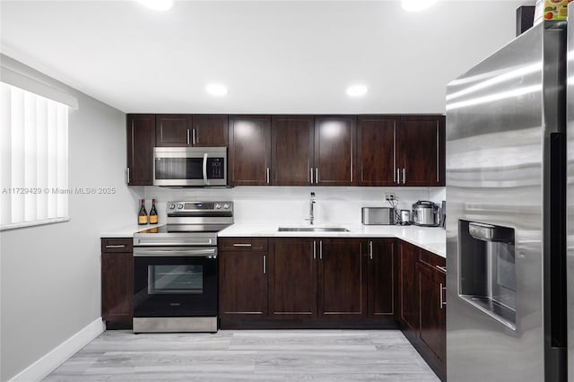 kitchen featuring appliances with stainless steel finishes, tasteful backsplash, light hardwood / wood-style floors, sink, and dark brown cabinets