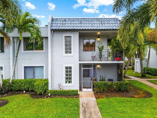 view of front of home with a balcony and a front lawn