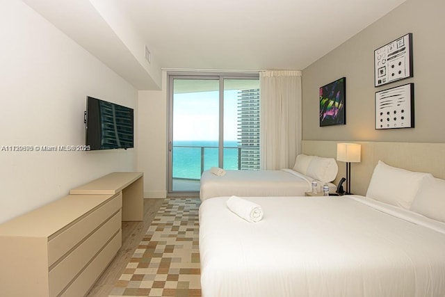 bedroom featuring floor to ceiling windows, light hardwood / wood-style floors, and access to outside