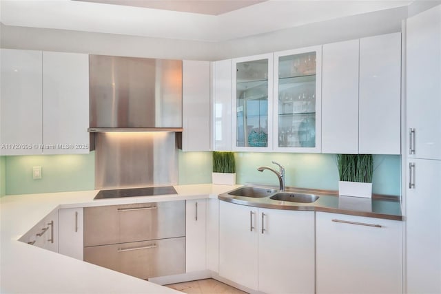 kitchen featuring sink, wall chimney range hood, white cabinets, and black electric cooktop