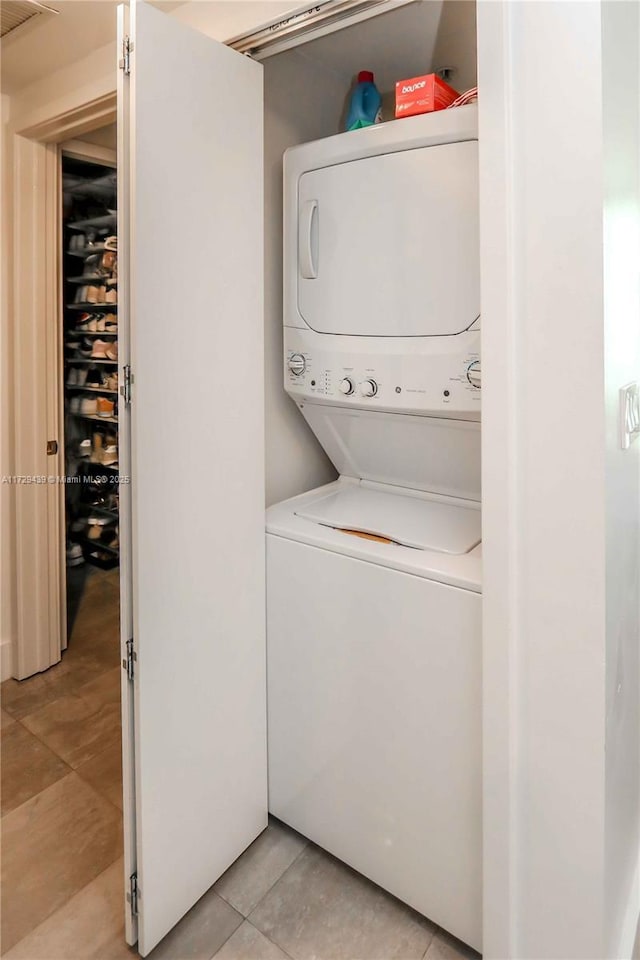 clothes washing area featuring stacked washer and dryer and light tile patterned flooring