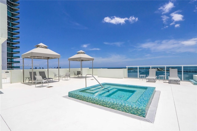 view of pool featuring a water view, a patio, and a hot tub