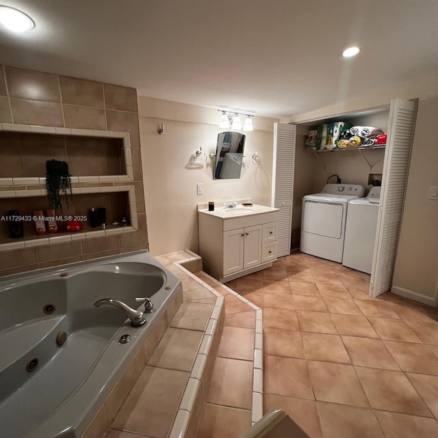 bathroom with tile patterned flooring, vanity, tiled bath, and washer and dryer