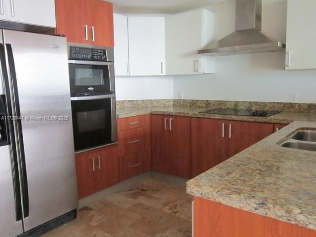 kitchen featuring stainless steel appliances, wall chimney exhaust hood, white cabinets, and light stone counters