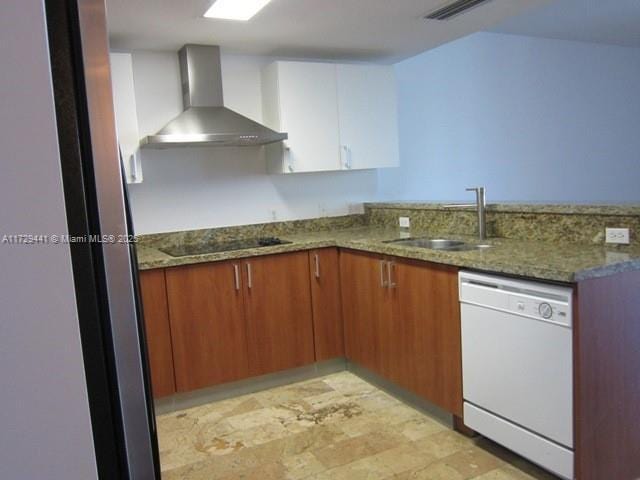 kitchen featuring dishwasher, wall chimney range hood, black electric stovetop, dark stone countertops, and sink