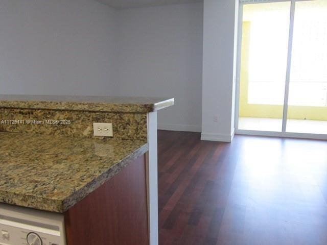 kitchen featuring light stone counters, dark wood-type flooring, and washer / dryer