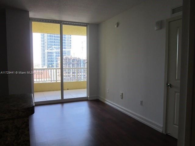 empty room with a wall of windows and hardwood / wood-style floors