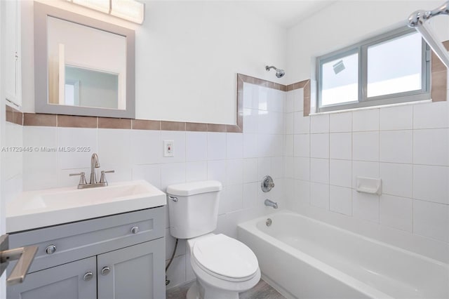 full bathroom featuring toilet, vanity, tile walls, and tiled shower / bath combo