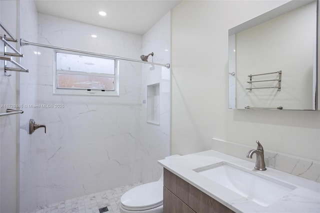 bathroom featuring toilet, vanity, and tiled shower