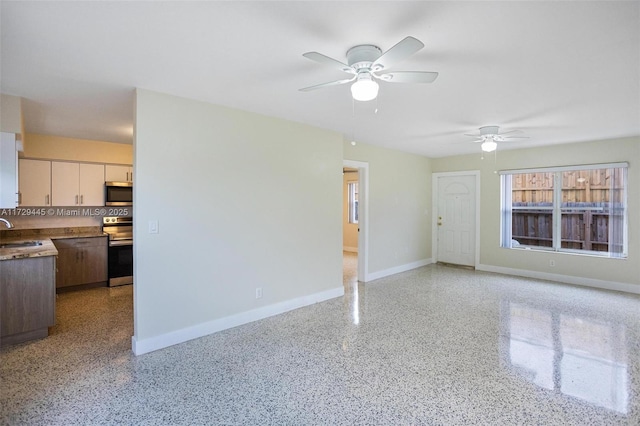 unfurnished living room featuring ceiling fan and sink