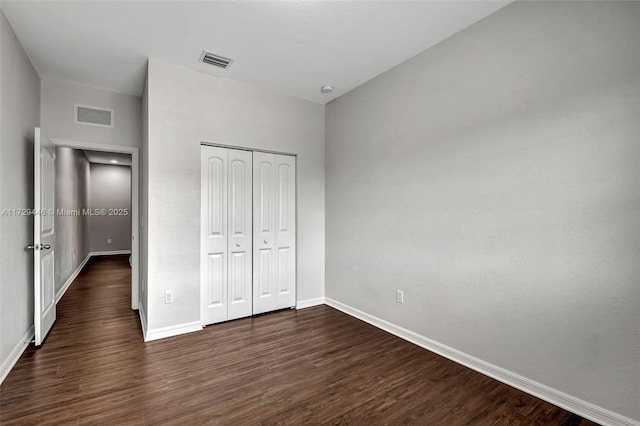 unfurnished bedroom with dark wood-type flooring and a closet