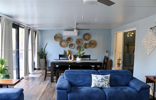 living room with ceiling fan, a wall mounted AC, and hardwood / wood-style flooring