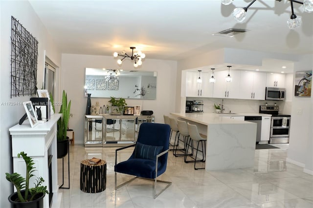 kitchen with decorative light fixtures, kitchen peninsula, a kitchen breakfast bar, stainless steel appliances, and white cabinets