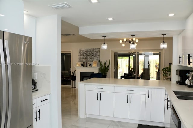 kitchen with decorative light fixtures, white cabinets, stainless steel fridge, and kitchen peninsula