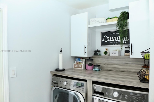 washroom with washer and dryer and cabinets