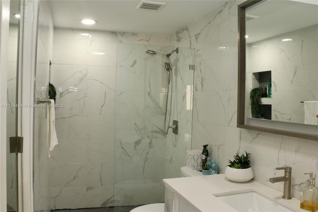 bathroom featuring toilet, vanity, and a tile shower