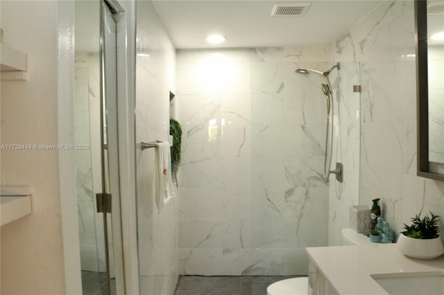 bathroom with tiled shower, vanity, and toilet