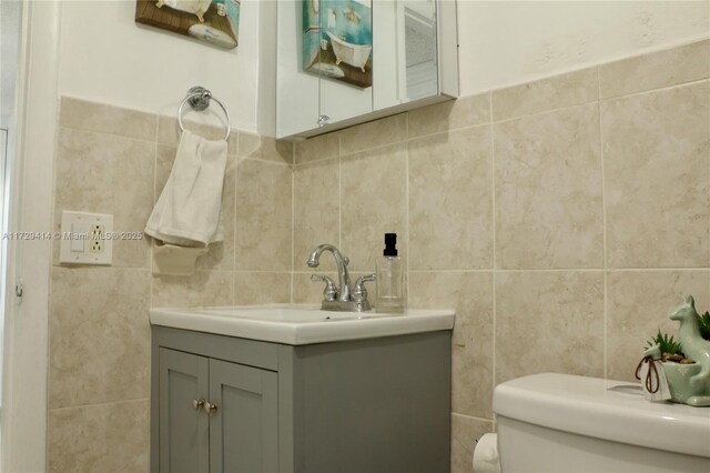 bathroom with tasteful backsplash, vanity, tile walls, and toilet