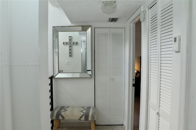 interior space with a textured ceiling and light tile patterned floors