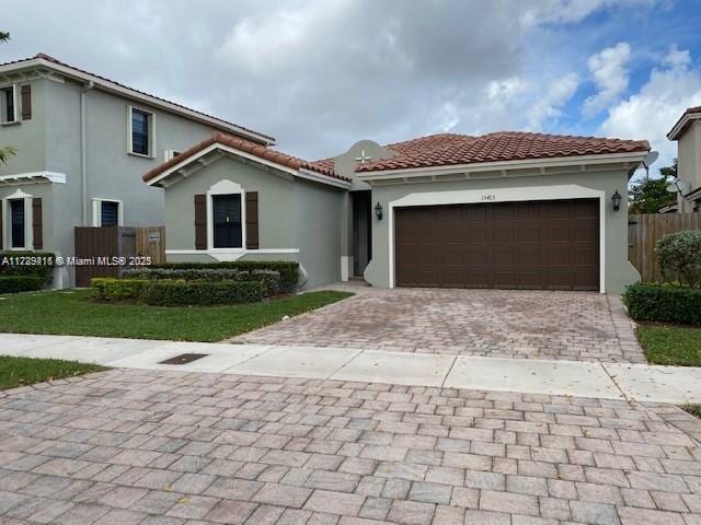 mediterranean / spanish-style home with fence, a garage, stucco siding, decorative driveway, and a tiled roof
