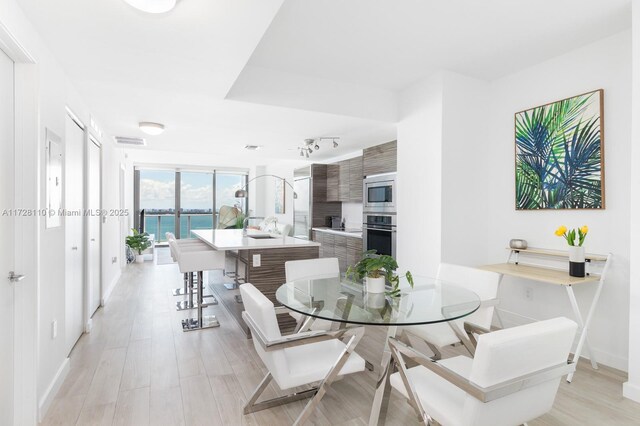 dining area featuring light hardwood / wood-style floors and a water view