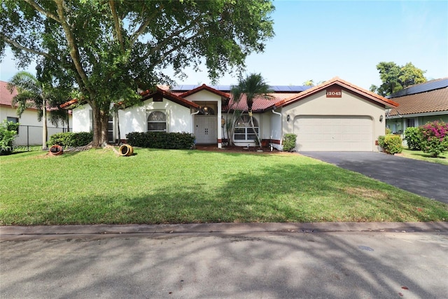 view of front of home featuring a front yard, a garage, and solar panels