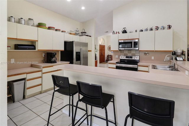 kitchen featuring a breakfast bar, decorative backsplash, sink, stainless steel appliances, and light tile patterned floors