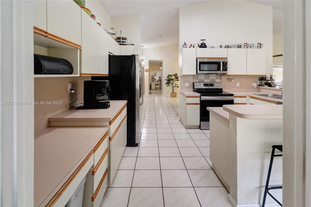 kitchen featuring appliances with stainless steel finishes, white cabinetry, decorative backsplash, sink, and light tile patterned flooring