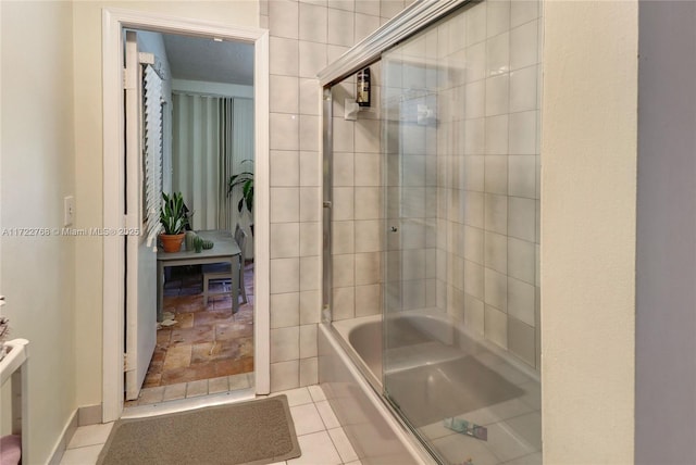 bathroom with bath / shower combo with glass door and tile patterned flooring