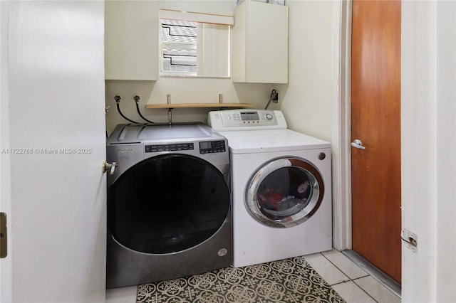 laundry area featuring light tile patterned flooring, washing machine and clothes dryer, and cabinets