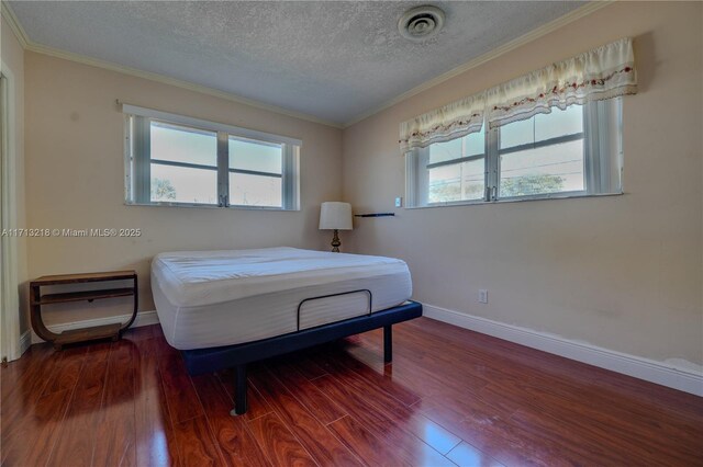 bedroom with crown molding, a textured ceiling, and hardwood / wood-style floors