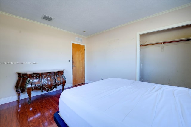 bedroom with a closet, dark hardwood / wood-style flooring, and crown molding