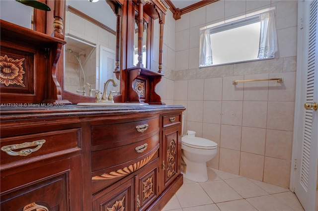 bathroom with toilet, vanity, tile walls, tile patterned flooring, and crown molding